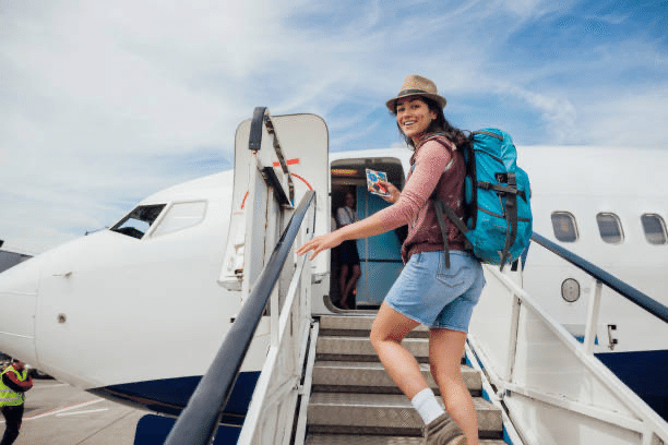 笑顔で飛行機のタラップを上る旅行者